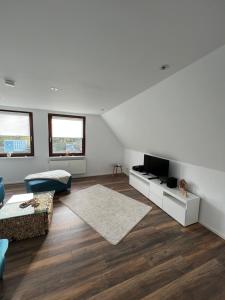a white living room with a couch and a tv at Appartementhaus Silberborn in Bad Harzburg