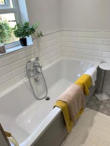 een wit bad met een handdoek en een plant bij Hilltop Cottage in Thropton