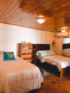 sypialnia z 2 łóżkami i drewnianym sufitem w obiekcie Coibahouse w mieście Santa Catalina