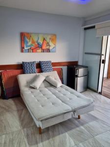 a bed in a room with a painting on the wall at Arraial churrasco e mar 49 e 53 in Arraial do Cabo +80 photos