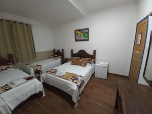a room with three beds and a table in it at Pousada Sinhá Moça Campos Ltda in São João del Rei +290 photos