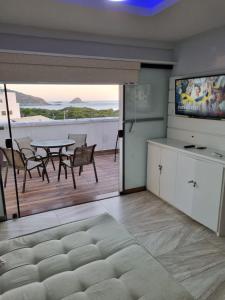 a living room with a television and a table with chairs at Arraial churrasco e mar 49 e 53 in Arraial do Cabo