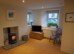 a living room with a fireplace and a television and a chair at Brook Cottage Askrigg in Askrigg
