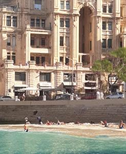 a group of people on the beach in front of a building at Sliema Bedrooms with ensuite bathrooms in Sliema