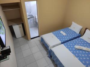 a small room with two beds and a bathroom at Pousada Simão in Maragogi