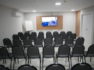 uma sala de conferências com cadeiras pretas e um ecrã em Açu Hotel em São João da Barra