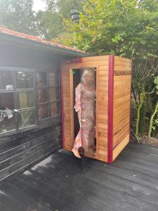 une femme debout à l'intérieur d'une maison en bois dans l'établissement Hipsy-Gipsy saunalodge, à Heede