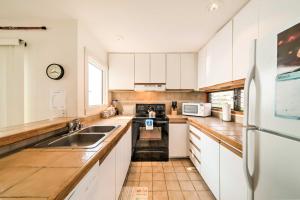 a kitchen with white cabinets and a sink and a refrigerator at Oceanfront Kailua-Kona Townhome with Pool and Views! in Kailua-Kona