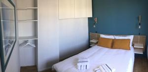um quarto com uma cama branca e uma parede azul em SUPERBE T3 LES PIEDS DANS L'EAU, parking, piscine en été em Lacanau-Océan