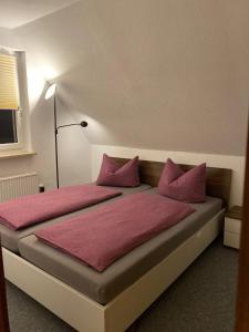 ein Schlafzimmer mit einem Bett mit rosa Kissen in der Unterkunft Am Fuße zur Napoleonschanze in Hohnstein