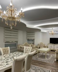 Apartment Balicevac Ilidza في سراييفو: غرفة معيشة فيها ثريا وطاولة وكراسي