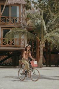 a woman riding a bike down the street at Aldea Kuká, Luxury Eco Boutique Hotel - Adults Only in Holbox Island