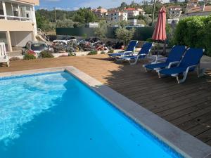 - une piscine avec des chaises et un parasol dans l'établissement Hotel Larverde, à Sertã