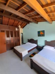 1 dormitorio con 2 camas y techo de madera en HOSTAL HELICONIAS, en Charalá