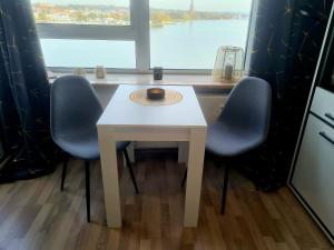 a white table with three blue chairs and a window at Ferienwohnung NEXUS in Schleswig