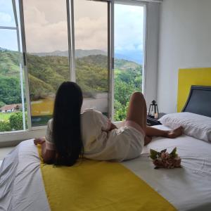 a woman laying on a bed looking out of a window at MIRADORES D ALESSANDRA in Pueblo Bello