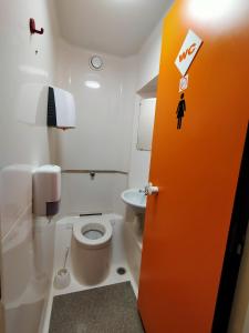 eine orangefarbene Tür im Bad mit WC in der Unterkunft HOTEL THANIA in Frontignan