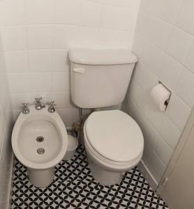 a bathroom with a white toilet and a black and white tile floor at Crespo Urbano in Buenos Aires