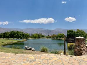 a sign in front of a lake with mountains in the background at Wayra huasi in Cafayate