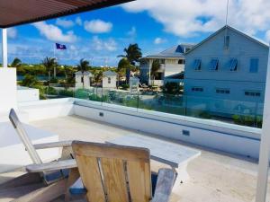 una silla de madera sentada en un balcón con vistas al océano en Casa Moderna Fresca and The PoolClub at Mahogany Bay! en San Pedro