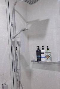 a shower with three bottles on a shelf in a bathroom at Cozy 1BR Apartment in the heart of Canberra in Canberra