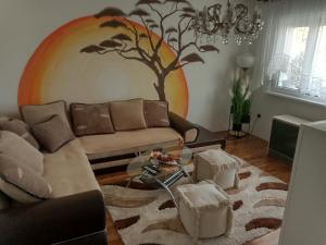 - un salon orné d'une fresque murale représentant les arbres dans l'établissement Apartman Hakuna Matata, à Sombor