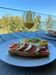 a white plate with a sandwich and a glass of wine at Lela lakeside apartman a vizek szerelmeseinek in Balatonlelle