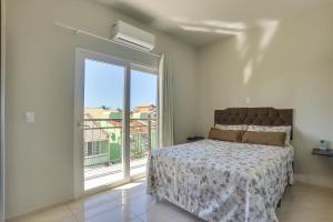 um quarto com uma cama e uma grande janela em Águas de Verão em Florianópolis