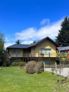 a large house with a porch and a yard at El Foye in Villa La Angostura