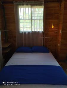 Cama azul en habitación con ventana en Cabañas Estrella de Mar, Palmar del viento, Moñitos, en Moñitos