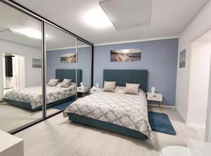two beds in a bedroom with blue walls and mirrors at Studio'24 - Adults Only in Constanţa