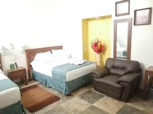 a hotel room with a bed and a chair at Casa Esmeralda Hotel in Oaxaca City