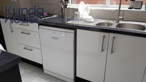 a kitchen with white cabinets and a sink at Kunda House Bournbrook in Birmingham