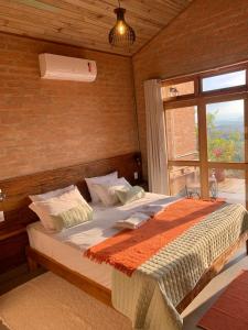 a bedroom with a large bed with a window at Casa Erva Doce Pousada in Delfinópolis