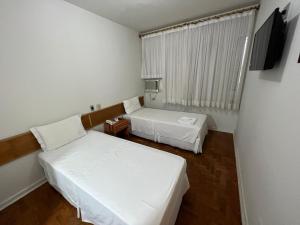 Habitación pequeña con 2 camas y TV. en Santa Rosa Hotel, en Assis