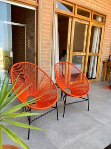 2 sedie arancioni sedute su un patio con una pianta di Casa Erva Doce Pousada a Delfinópolis