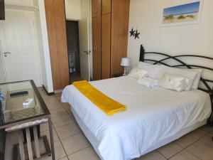a bedroom with a bed with a yellow blanket on it at Beachside 3 bed apartment with stunning seaviews in Amanzimtoti