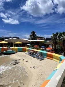 einen Strand mit Liegestühlen und Sonnenschirmen auf dem Sand in der Unterkunft Sand Bar Condo - 1BR Suite next to The Morgan Resort in Maho Reef