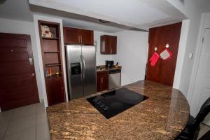 a kitchen with a granite counter top and a stainless steel refrigerator at Sand Bar Condo - 1BR Suite next to The Morgan Resort in Maho Reef