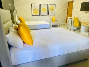 two beds with yellow pillows in a hotel room at El Paso Hotel 