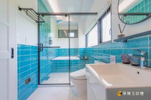 bagno con pareti piastrellate blu, servizi igienici e lavandino di Mika BnB a Shih-t'ou-wei