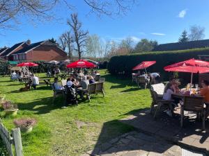 a group of people sitting at tables with red umbrellas at The White Hart in Alton