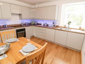 a kitchen with white cabinets and a wooden table at Flat Above 27 in Bishop Auckland