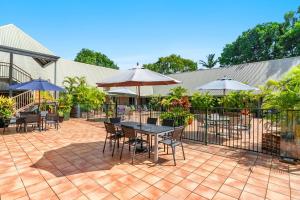 a patio with tables and chairs and umbrellas at Byron Central Apartments in Byron Bay