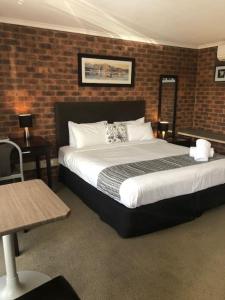 a bedroom with a large bed and a brick wall at Admiral Motor Inn in Rosebud