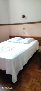 a bedroom with a bed with a white blanket on it at Hotel Bandeirante in Oliveira +6 photos