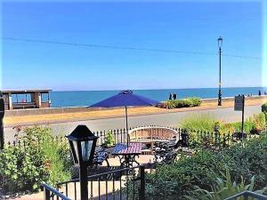 a table and chairs with an umbrella on the beach at Stratford House Exclusively for Adults in Llandudno