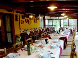 a long dining room with tables and chairs with plates and wine bottles at Su Leunaxiu in Solèminis