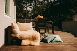 una silla y almohadas en un porche con mesa en Casa confortável em local tranquilo., en Rodeio