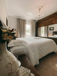 um quarto com uma grande cama branca com um vaso de flores em Casa confortável em local tranquilo. em Rodeio